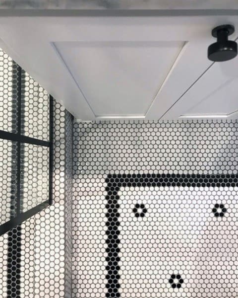 White hexagonal mosaic floor tiles with black accents in small bathroom.