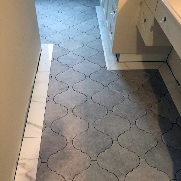 Natural stone bathroom floor with intricate grey tile pattern.