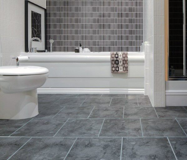 Simple bathroom with grey floor tiles and white bathtub featuring a towel rack.