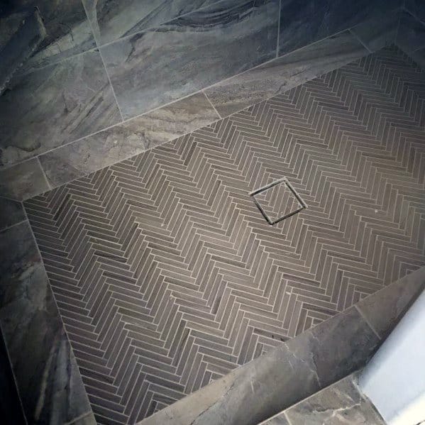 Shower floor with grey chevron-patterned tile and square drain.