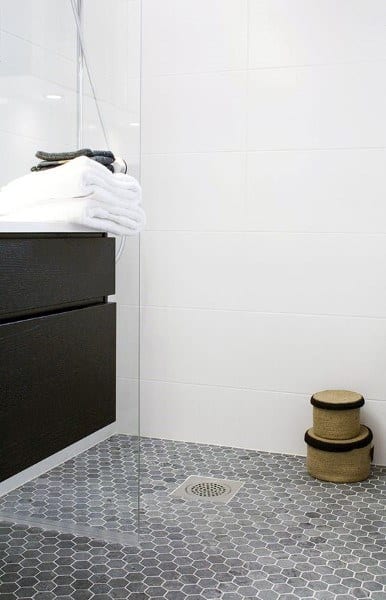 Shower with grey hexagonal floor tiles and white walls.