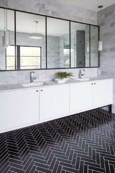 Modern bathroom with large double vanity, black chevron floor tiles, and mirrored backsplash.