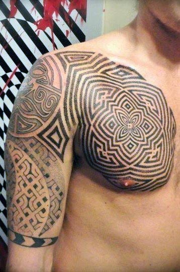 A person's shoulder and chest with intricate geometric and tribal tattoos