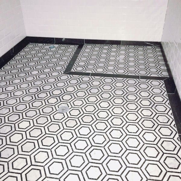 Hexagonal patterned black and white bathroom floor tiles with geometric design.