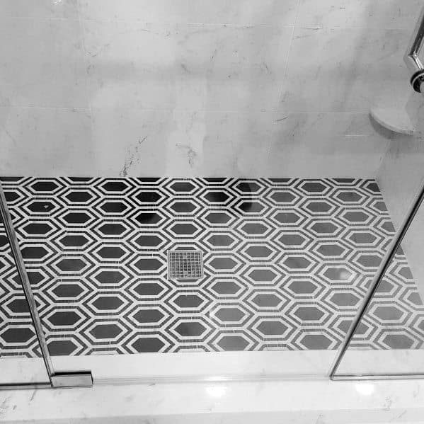 Hexagonal patterned black and white shower floor tiles inside a glass enclosure.