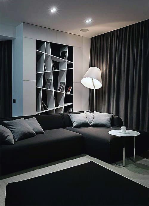 Modern living room with dark sofa, geometric shelves, large lamp, and a small round table with a cup