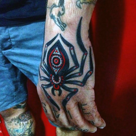 Black and red spider tattoo on the back of a hand