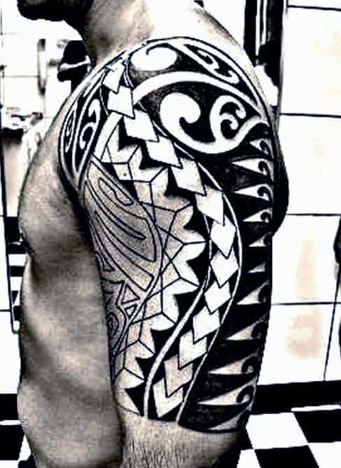 A man with an intricate tribal tattoo sleeve on his right shoulder