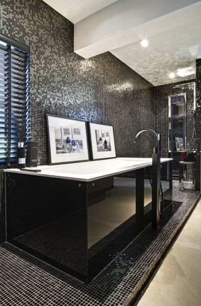 Large black bathtub with mosaic tile walls and modern minimalist decor.