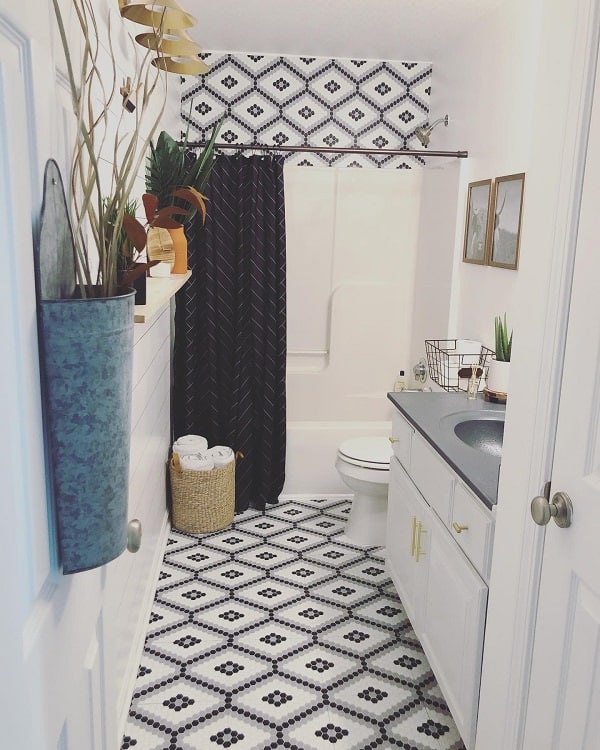 Small bathroom with black and white mosaic floor tiles, dark shower curtain, and modern decor.