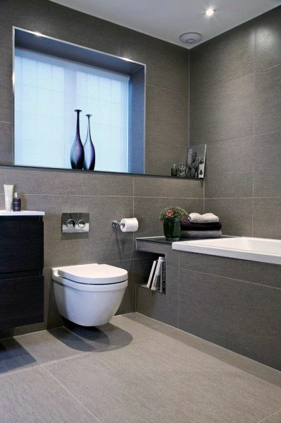 Modern bathroom with grey tiles, floating vanity, and built-in bathtub.