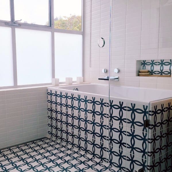 Modern bathroom with blue and white patterned floor and bathtub tiles.