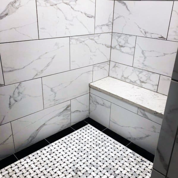 Marble tile shower with built-in bench and mosaic floor tiles.