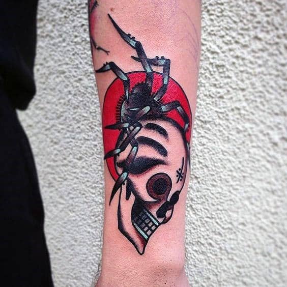 Forearm tattoo of a spider over a skull with a red circle in the background