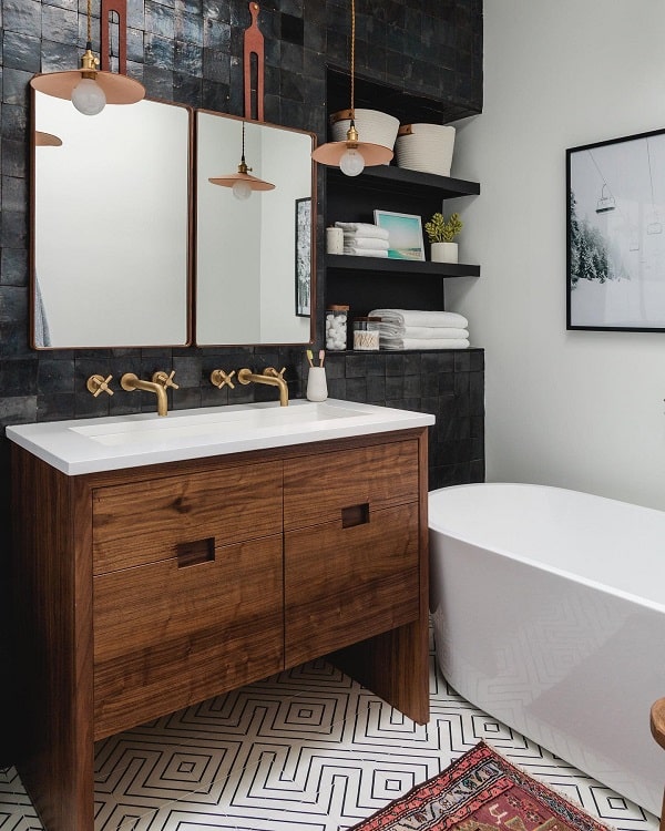 Modern bathroom with low-hanging lights, wooden vanity, and geometric floor tiles.