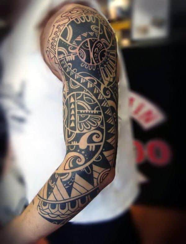 Arm with an intricate, black geometric and tribal-style tattoo design