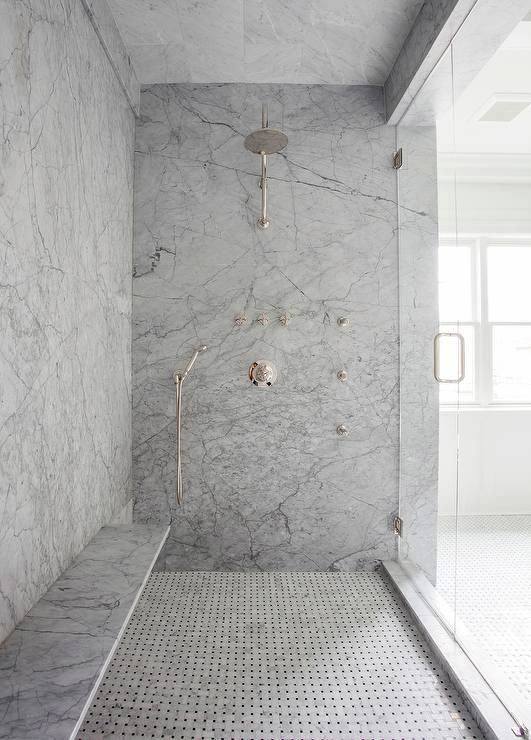 Large marble shower with built-in bench, rainfall showerhead, and mosaic floor tiles.