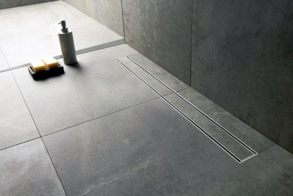 Slate bathroom floor tiles with linear drain and minimal design.