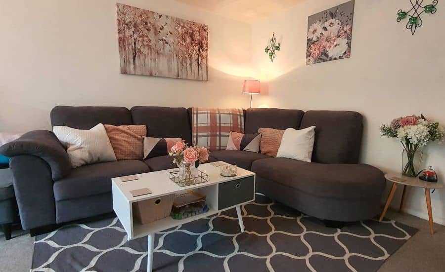 Cozy living room with a dark sofa, floral decor, white coffee table, and soft lighting