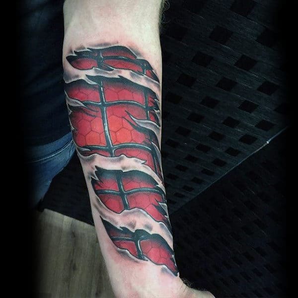 Forearm tattoo of torn skin revealing a red and black mechanical design underneath