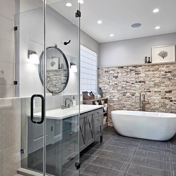 Modern bathroom with freestanding tub, stone feature wall, and glass shower enclosure.