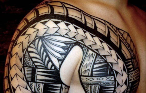 A person displaying a complex, geometric shoulder tattoo in black ink