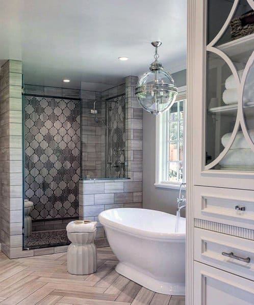 Bathroom with freestanding tub, patterned shower tiles, and chevron floor design.