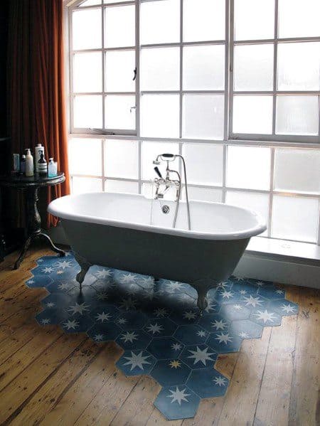 Freestanding bathtub on star-patterned hexagonal tiles with wood floor transition.