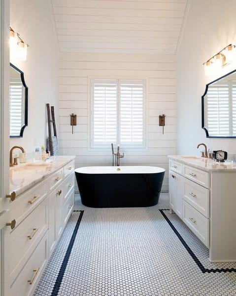 Modern bathroom with black freestanding tub, double vanities, and hexagonal mosaic floor tiles.