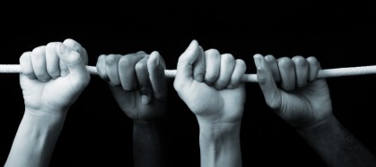 The hands of two people grasping a rope