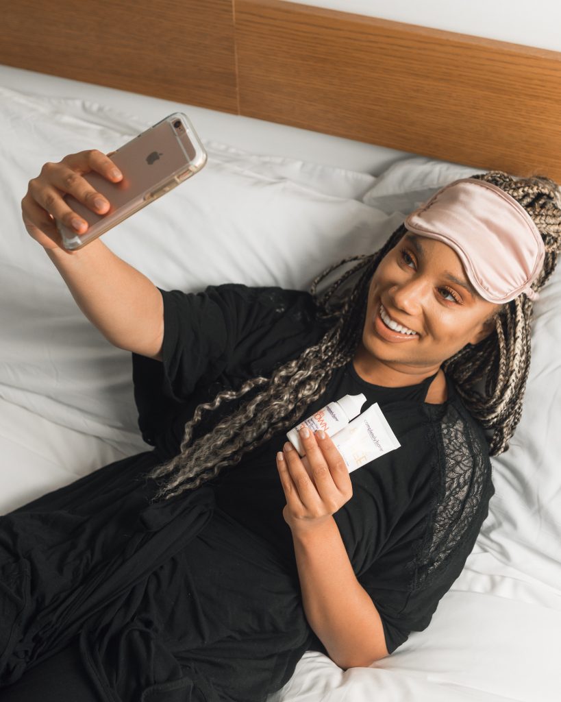 a woman taking a selfie while holding makeup