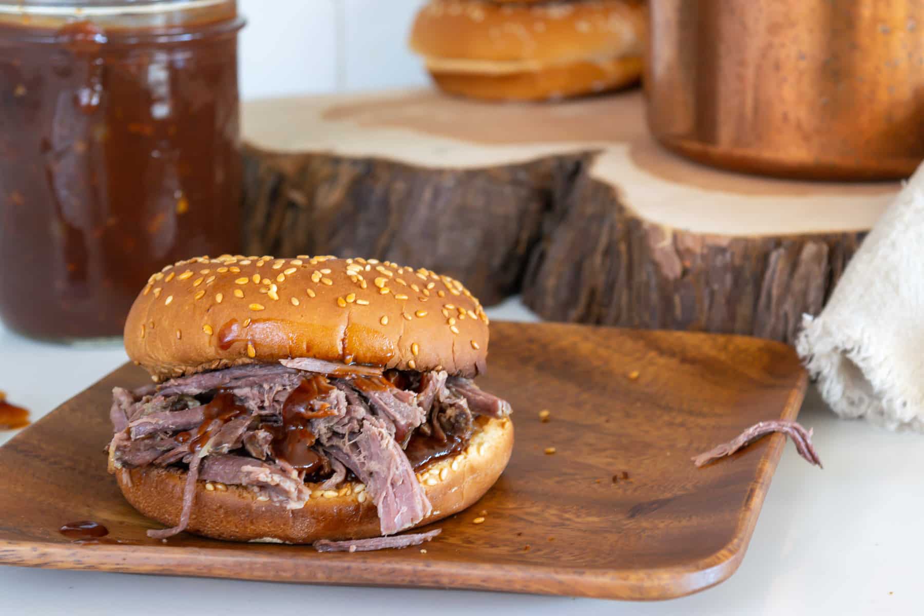 A bbq sandwich sitting on top of a wooden plate.