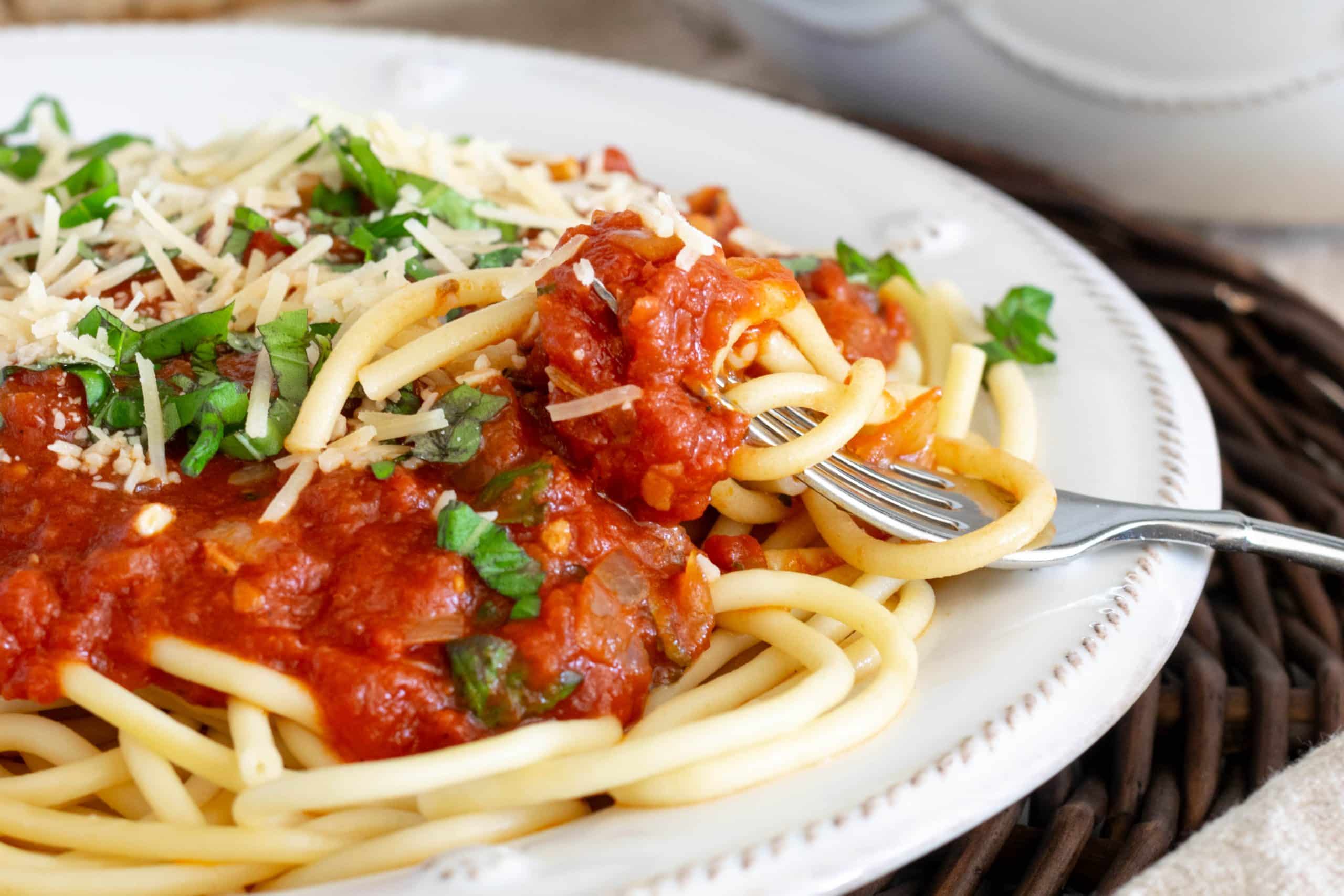 Spaghetti Arrabiata on a plate with pasta twirled around a fork.