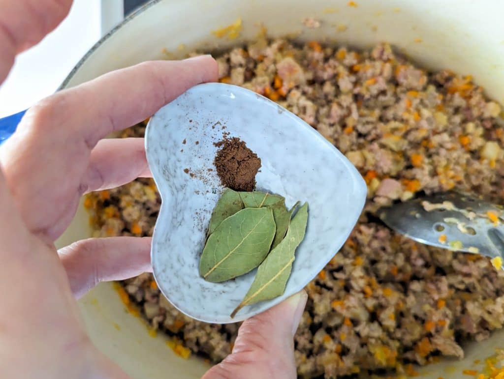 Bay leaves and nutmeg being added to bolognese.