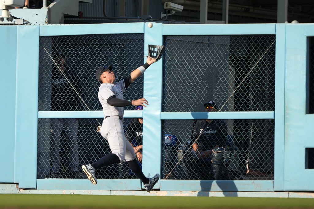 Aaron Judge crashes through the wall after making a running catch in the eighth inning of the Yankees' win.