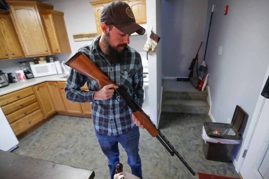 Army Reserves Lt. Nicolas Talbott checking his pump shotgun at home, a plaintiff challenging the military transgender ban