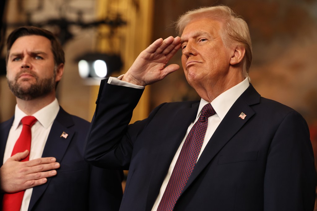 President Donald Trump saluting while Vice President JD Vance listens to the national anthem during their inauguration ceremony in the U.S. Capitol Rotunda