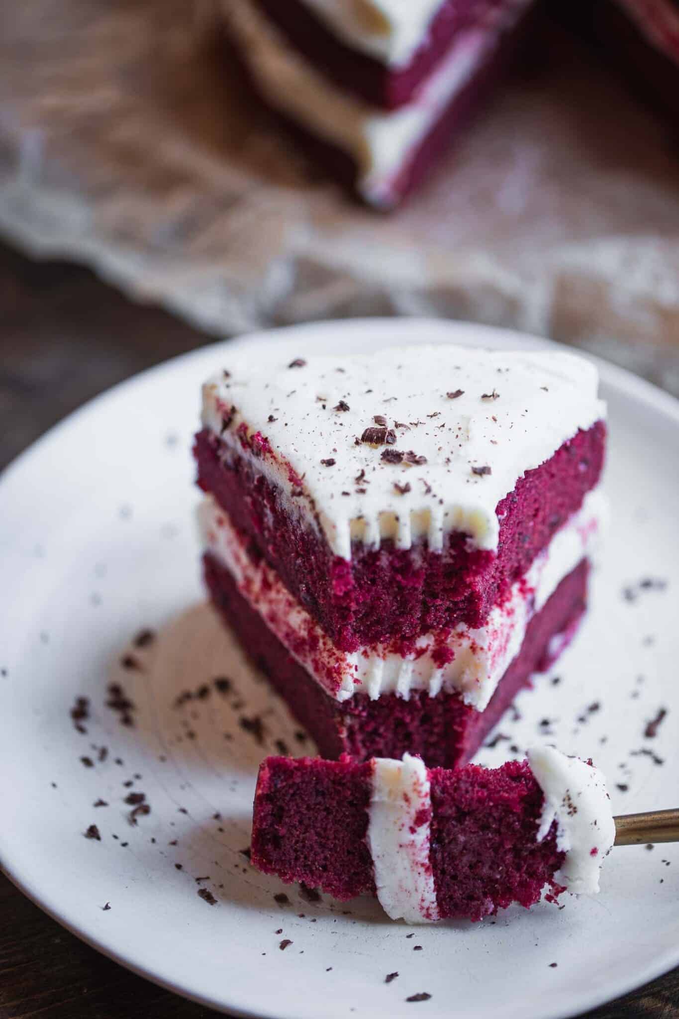 taking a bite out of a slice of vegan red velvet cake