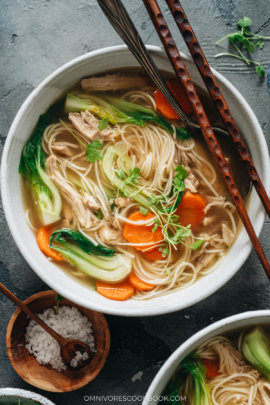 Bowl of noodle soup with shredded chicken, carrot and baby bok choy