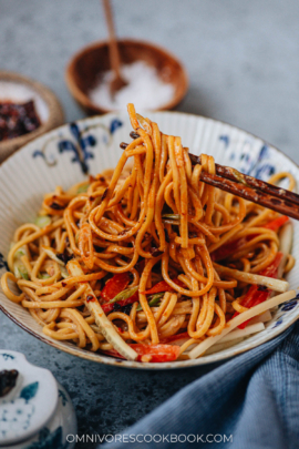 Using chopsticks to stretch peanut noodles from a bowl