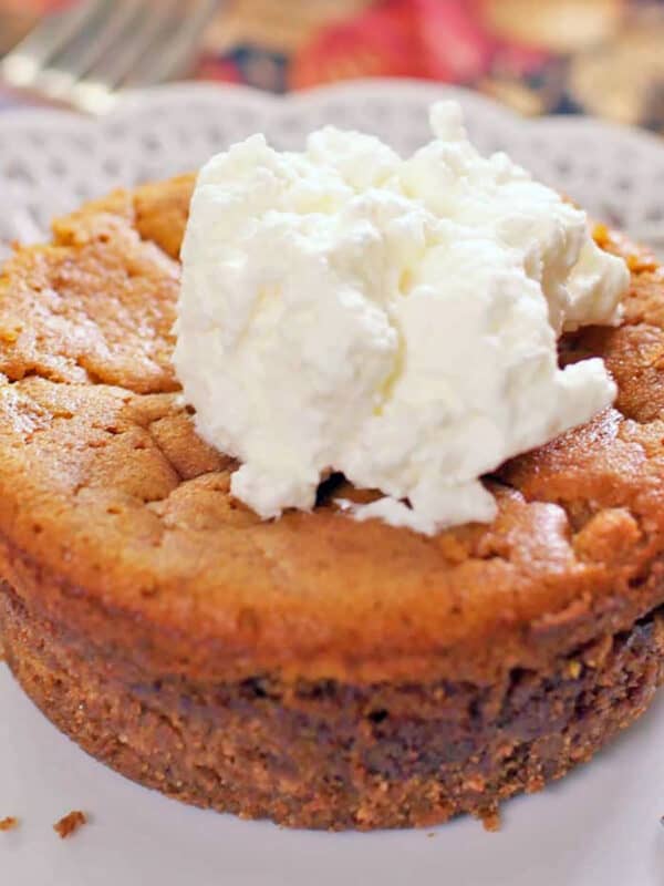 a mini pumpkin pie on a white plate next to a bowl of small miniature pumpkins.