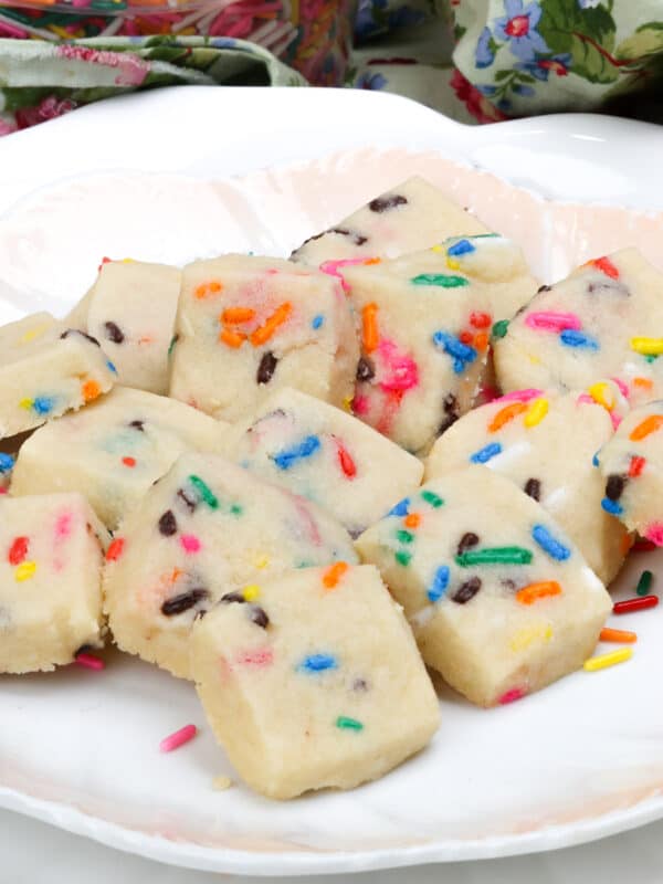 a plate of funfetti shortbread bites next to a container of colorful sprinkles.