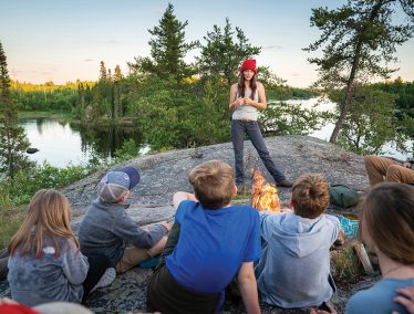 Ashley Bredemus speaks in front of group of boys in the wilderness