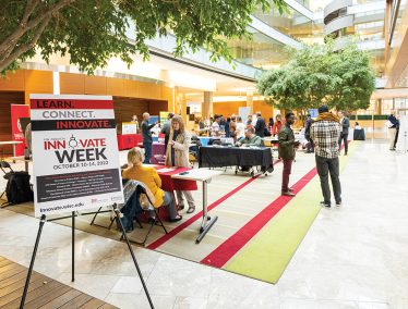 Tables and signs set up in the main lobby area of the Discovery Building as groups of people converse