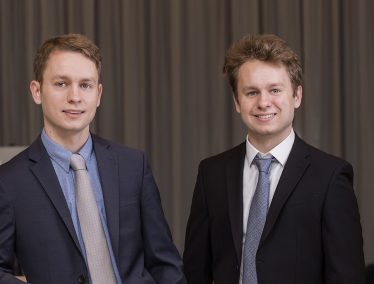 James and Chris Kardatzke smile wearing suits