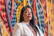 Portrait of Patricia Norby standing in front of a colorful art piece