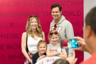 A family poses for a portrait in front of a red backdrop