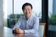 Headshot of Lawrence Wong seated at a table, smiling at the camera.