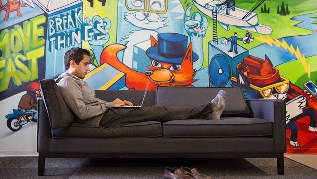 A man sitting on a couch concentrating on his computer behind a snazzy background