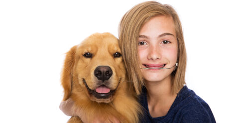 image of a child hugging a dog wearing orthodontic headgear and smiling at the camera